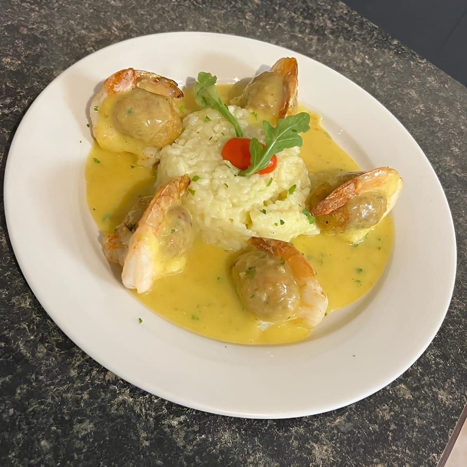 Luca Trattoria & Pizzeria's shrimp and risotto dish, garnished with arugula and a cherry tomato.